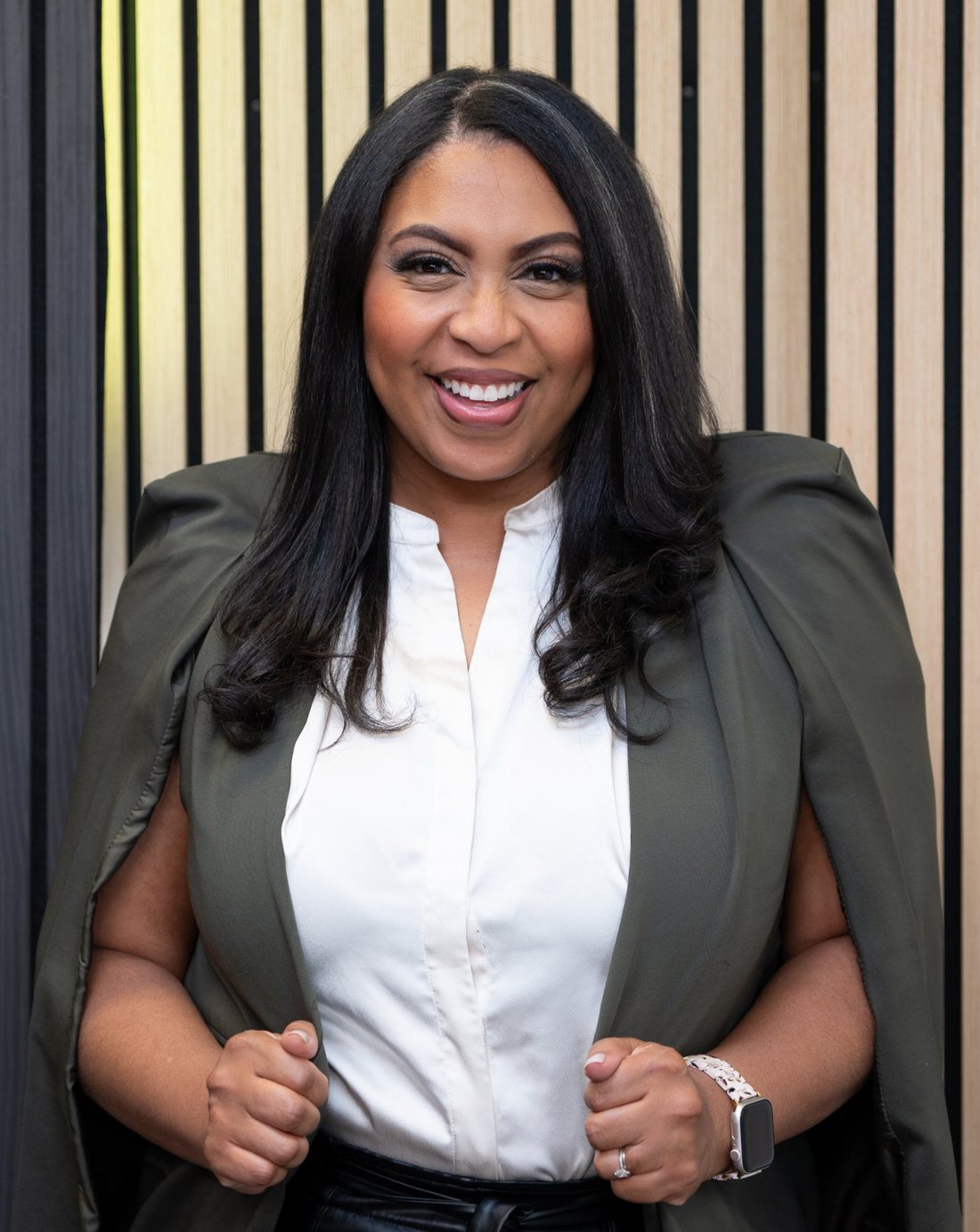 Alexis Rogers smiling in an olive cape blazer